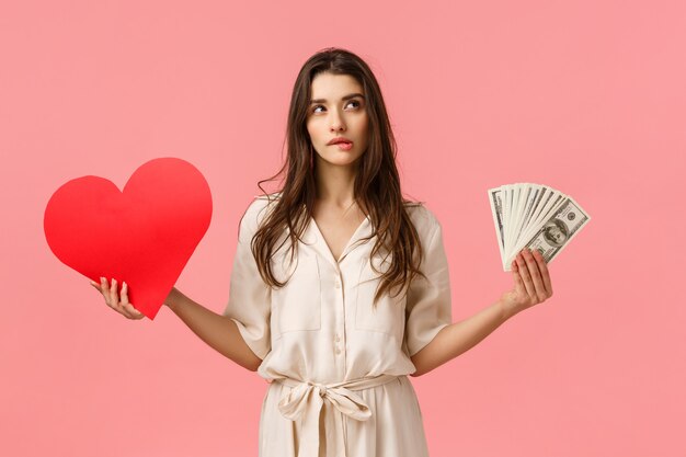 Atractiva mujer morena guapa vestida, con dinero en efectivo, dinero y corazón de amor