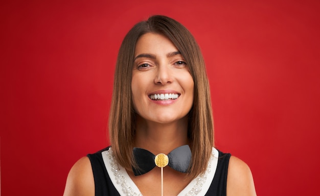 Atractiva mujer morena posando con aparatos fotográficos de Año Nuevo sobre fondo rojo.