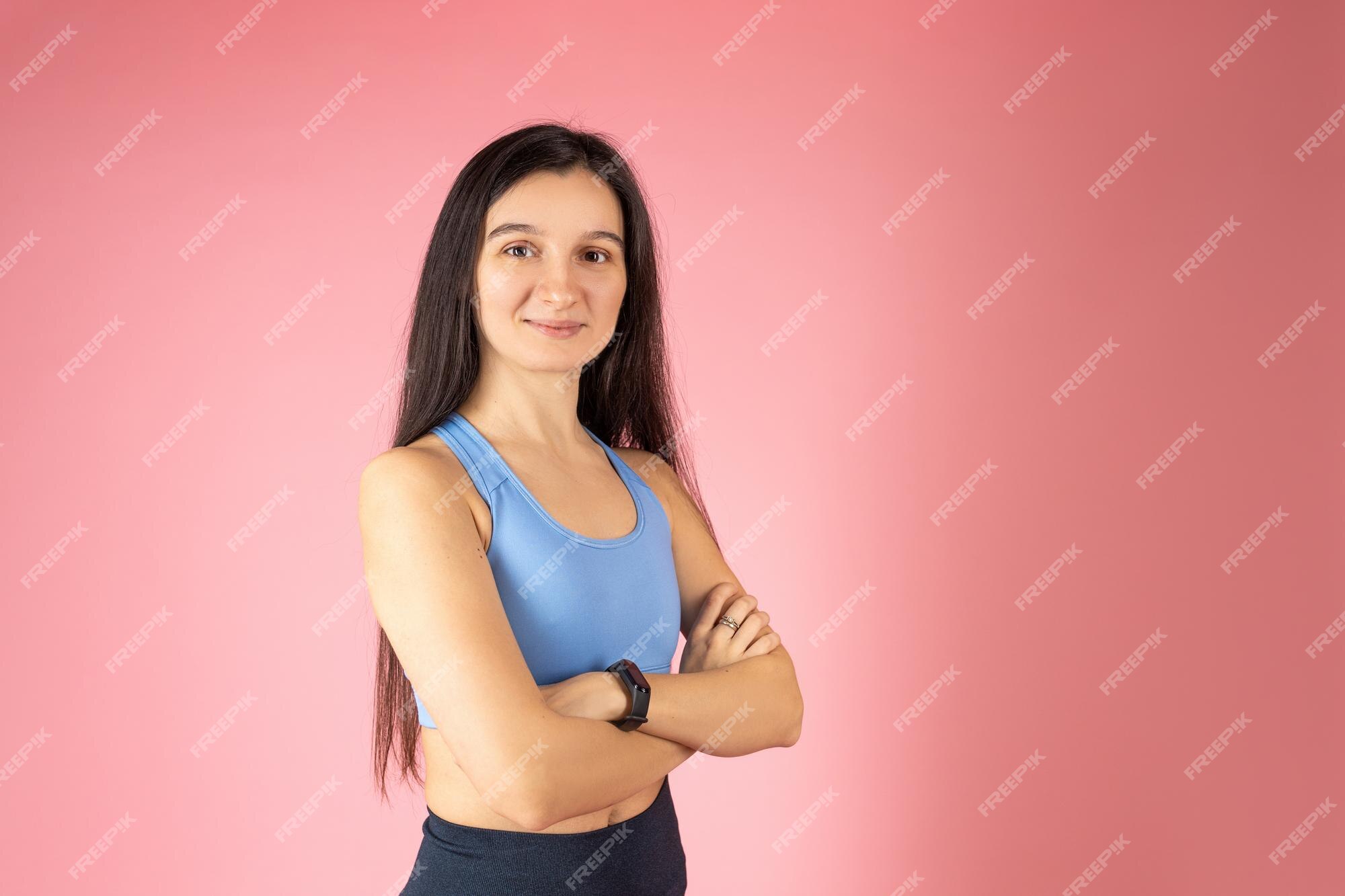 Atractiva mujer morena en ropa deportiva de moda sobre rosa concepto de estilo de vida saludable cara feliz sonriendo con los brazos cruzados mirando a la cámara persona positiva | Foto