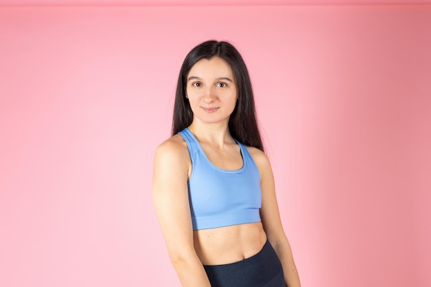 Atractiva mujer morena en ropa deportiva de moda sobre fondo rosa Concepto de estilo de vida saludable Persona positiva