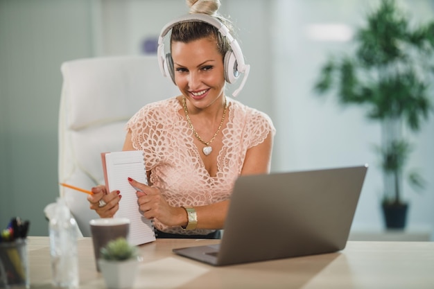 Una atractiva mujer de negocios con auriculares que trabaja en un centro de llamadas y habla con un cliente en línea en su computadora portátil.