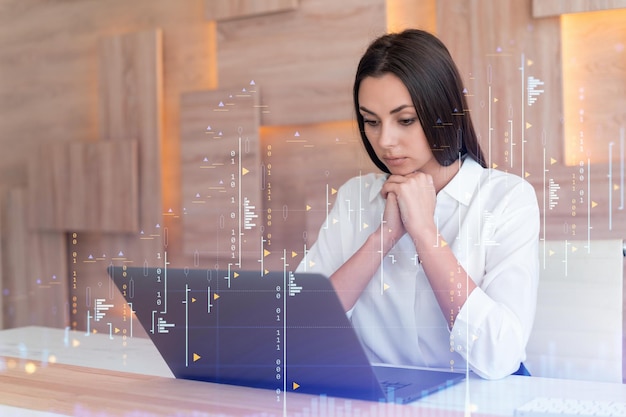 Foto atractiva mujer de negocios con camisa blanca en el lugar de trabajo que trabaja con una computadora portátil para optimizar la estrategia comercial en el fondo de finanzas corporativas holograma de gráfico forex sobre los antecedentes de la oficina