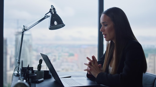 Atractiva mujer de negocios hablando con un socio comercial en video chat en la oficina