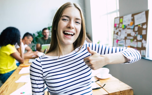 Atractiva mujer de negocios moderna confiada en ropa casual mira a la cámara y sonriendo. Equipo empresarial moderno de puesta en marcha. Compañeros de trabajo o estudiantes