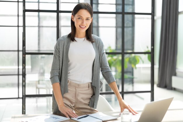 Atractiva mujer de negocios sonriendo mientras está de pie en la oficina