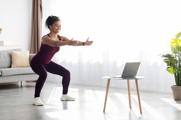 Atractiva mujer negra entrenando en casa con clase de fitness en línea