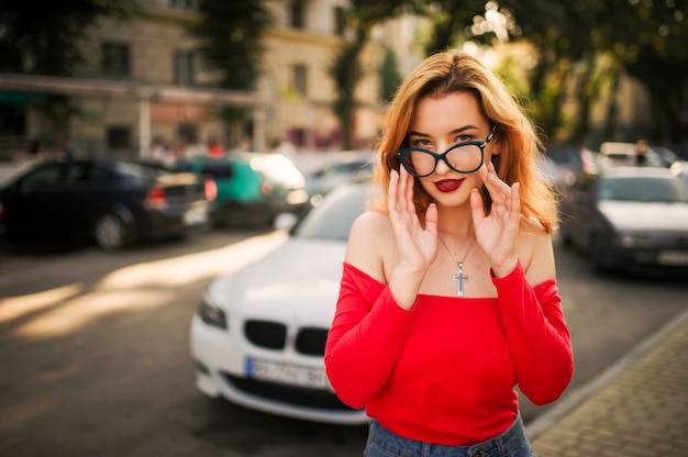 Atractiva mujer pelirroja en anteojos con blusa roja