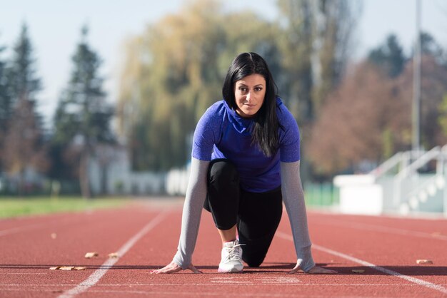 Atractiva mujer preparándose para la carrera en el área del parque de la ciudad entrenando y haciendo ejercicio para el concepto de estilo de vida saludable de resistencia al aire libre