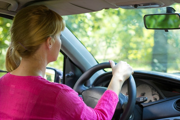 Atractiva mujer en rosa disfrutando del paseo en su carro.