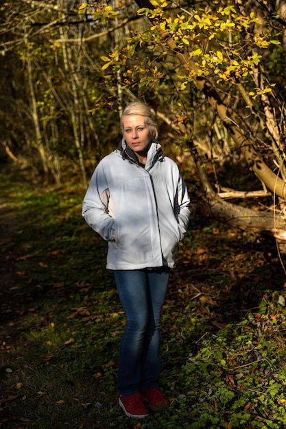 Atractiva mujer rubia caminando por el bosque en una caminata por la naturaleza