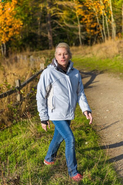 Foto atractiva mujer rubia caminando por el bosque en una caminata por la naturaleza