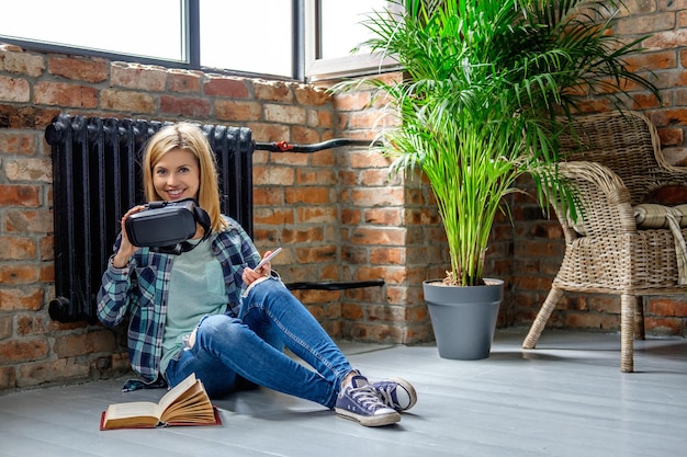 Atractiva mujer rubia casual sentada en el suelo y leyendo un libro en la sala de estar.