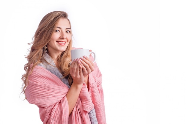 Atractiva mujer rubia envuelta en una manta sosteniendo la taza
