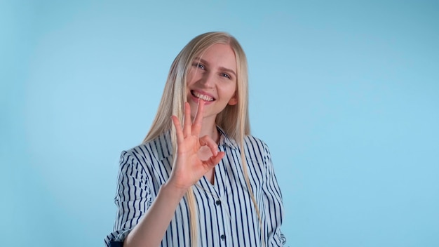 Atractiva mujer rubia haciendo el signo de la mano bien