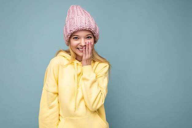 Atractiva mujer rubia joven feliz sonriente que se encuentran aisladas sobre fondo de colores vistiendo de pared