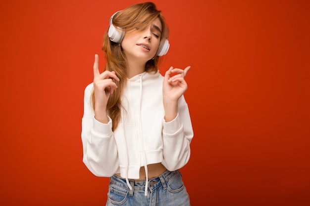 Atractiva mujer rubia joven positiva emocional con sudadera con capucha blanca