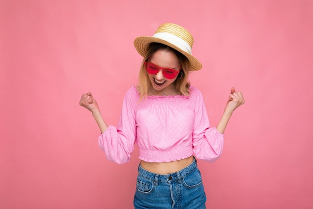 Atractiva mujer rubia joven sonriente feliz vistiendo ropa casual de verano y elegantes gafas de sol aisladas