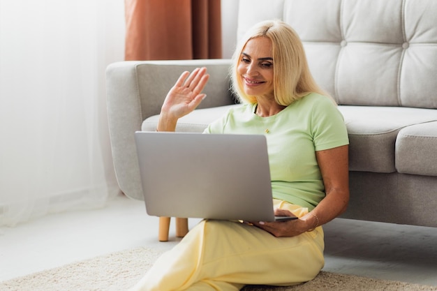 Atractiva mujer rubia de mediana edad usa laptop y videollamada