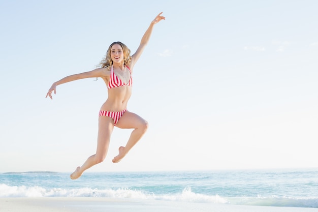 Atractiva mujer rubia saltando en la playa