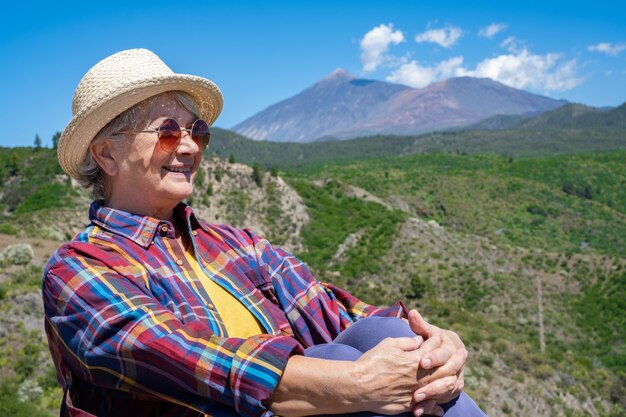 Atractiva mujer senior con sombrero de paja disfrutando de una excursión al aire libre en la montaña