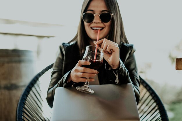 Foto atractiva mujer sentada en una cafetería moderna y trabajando en una laptop