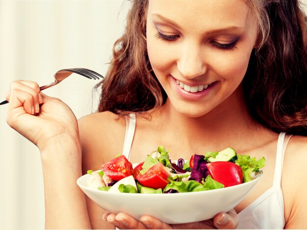 Atractiva mujer sonriente caucásica con ensalada aislado