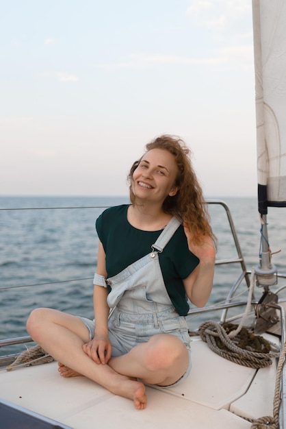 Una atractiva mujer sonriente está mirando a la cámara mientras está sentada en un yate Turismo de viajes y concepto de verano