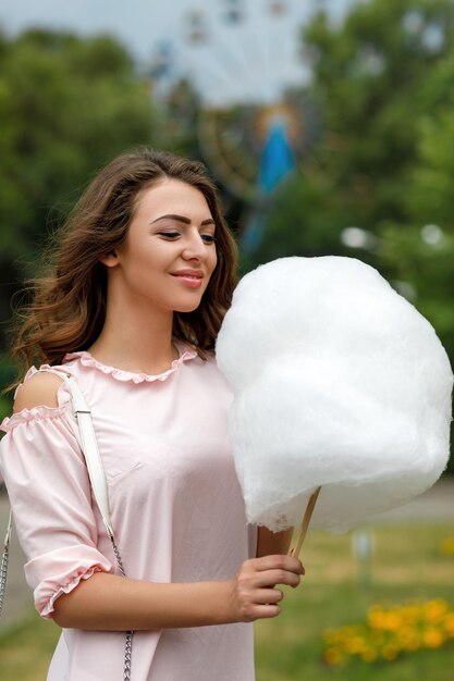 Atractiva mujer sosteniendo dulce algodón de azúcar