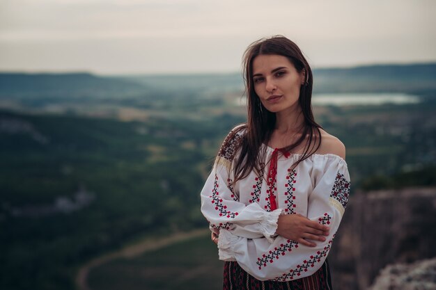 Atractiva mujer en traje rumano tradicional sobre fondo borroso verde montaña