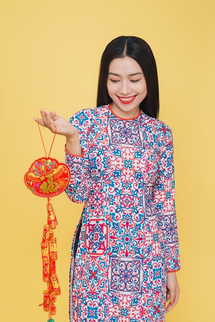 Atractiva mujer vietnamita con traje tradicional, aislado sobre fondo amarillo
