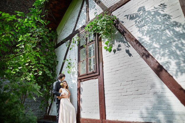 Atractiva novia y el novio de pie cerca uno del otro en el fondo del parque, foto de boda, hermosa pareja, día de la boda.