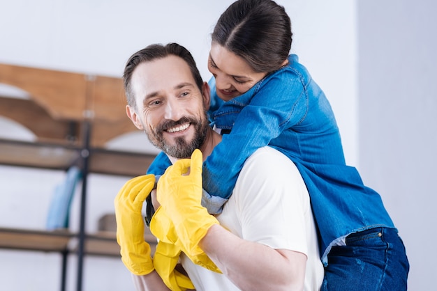 Foto atractiva pareja agradable agradable mirando directamente mientras se visten con guantes y esposo abrazando a esposa