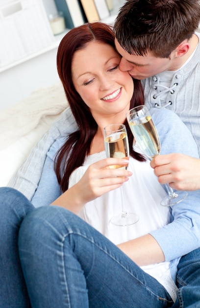 Atractiva pareja bebiendo champán tumbado en el sofá