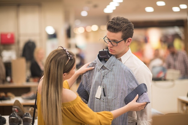 Atractiva pareja de compras en la tienda de ropa de un hombre