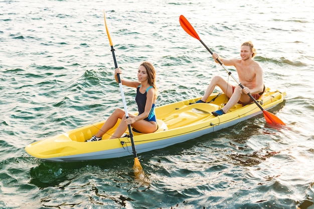 Atractiva pareja deportiva en kayak en el mar juntos