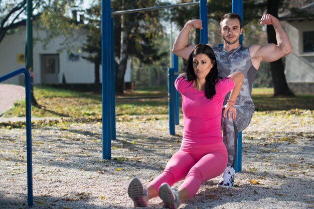 Atractiva pareja haciendo ejercicio Crossfit con Dips Bar en el área del parque de la ciudad entrenando y haciendo ejercicio para el concepto de estilo de vida saludable de resistencia al aire libre