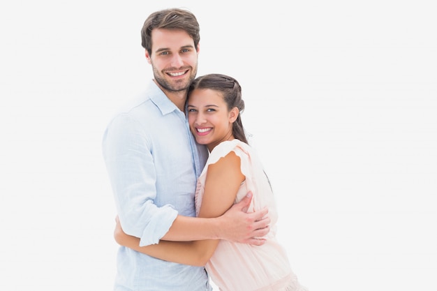 Atractiva pareja joven abrazos y sonriendo a la cámara