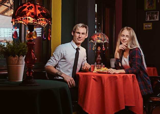 Atractiva pareja joven comiendo nachos durante las citas en un restaurante mexicano.