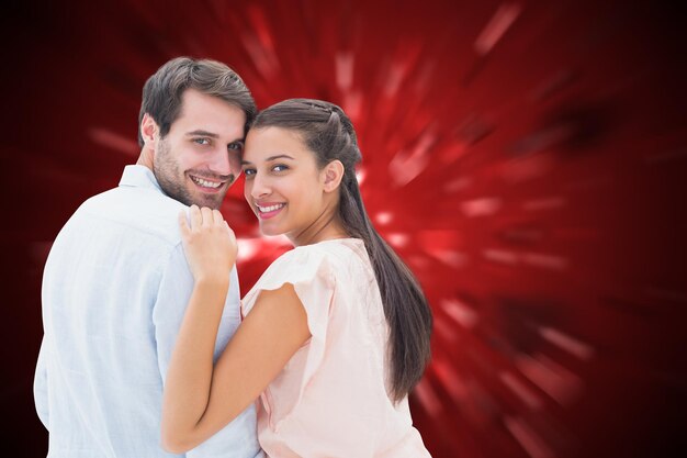 Atractiva pareja joven sonriendo a la cámara contra el diseño del corazón de San Valentín