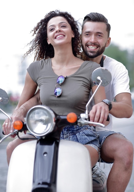 Foto atractiva pareja montando una moto en un día soleado en la ciudad