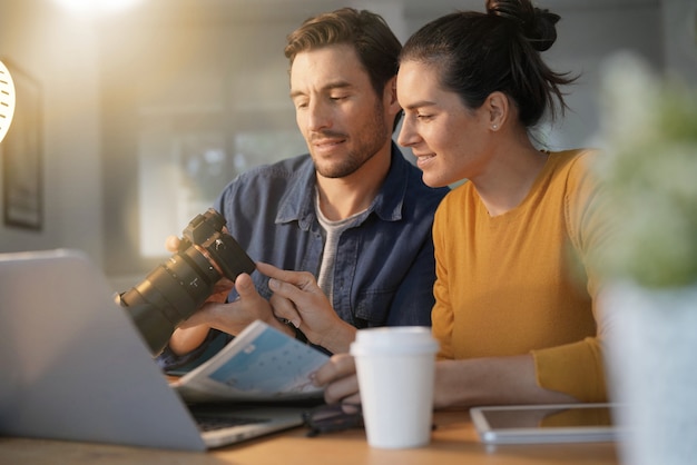 Foto atractiva pareja pasando fotos en su cámara en casa.