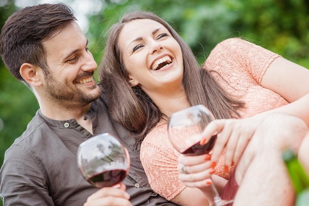 Atractiva pareja de picnic bebiendo vino tinto