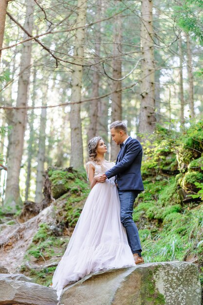 Una atractiva pareja de recién casados, un momento feliz y alegre. Boda de estilo bohemio en el bosque al aire libre.