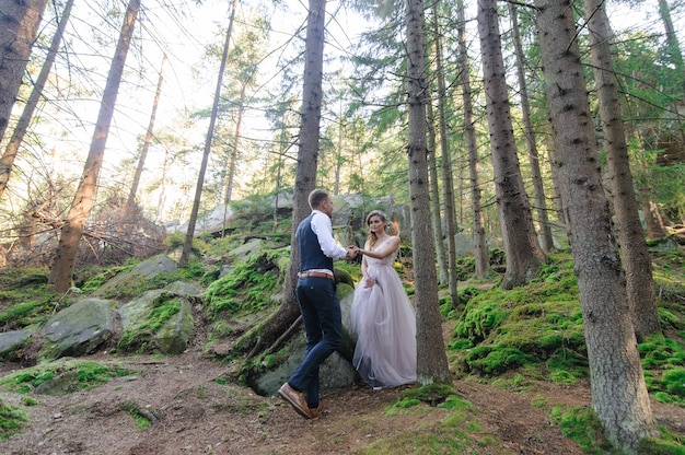 Una atractiva pareja de recién casados, un momento feliz y alegre. Boda de estilo bohemio en el bosque al aire libre.