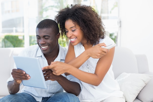 Atractiva pareja sentada en el sofá mirando juntos tablet