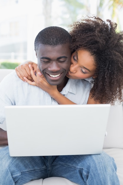 Atractiva pareja usando laptop juntos en el sofá