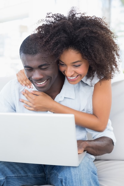 Atractiva pareja usando laptop juntos en el sofá