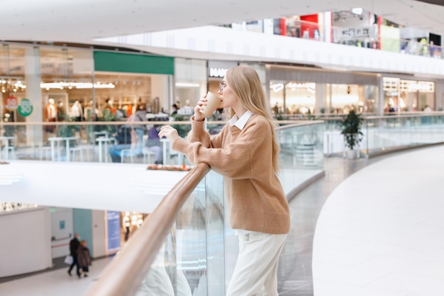 Atractiva rubia con una taza de café en un centro comercial