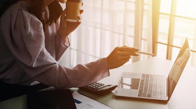 Atractiva y sonriente mujer de negocios asiática joven que trabaja en la oficina en casa Mujer asiática que trabaja en una computadora portátil con tableta