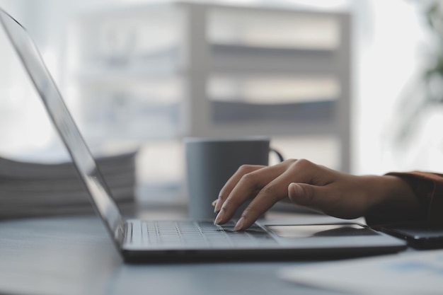 Atractiva y sonriente mujer de negocios asiática joven que trabaja en la oficina en casa Mujer asiática que trabaja en una computadora portátil con tableta